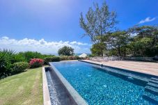 Piscina desbordante con vista al mar y jardín tropical florecido
