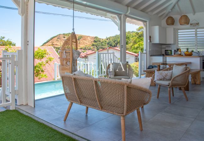 View of the outdoor living room, pool and kitchen area in a high-end villa in the West Indies, for a luxury outdoor living experience.