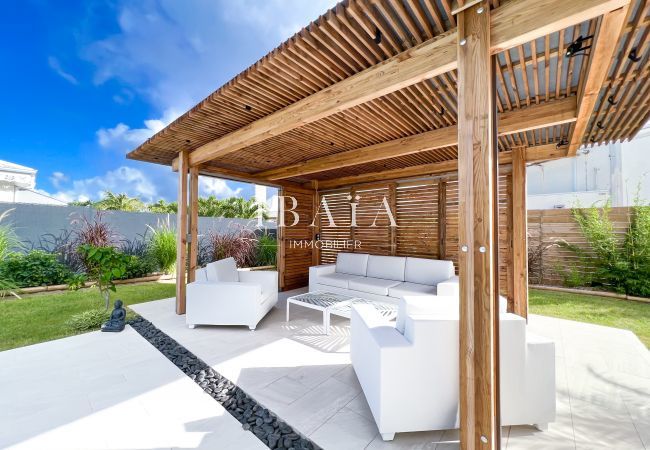 View of the outdoor living room on the edge of the terrace with a wooden pergola in an upscale villa in the West Indies, for moments of outdoor relaxa
