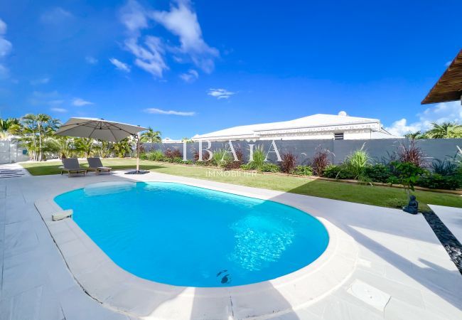 A view of the pool with a deckchair at the back and a parasol in a luxury villa in the West Indies, for relaxing moments under the tropical sun.