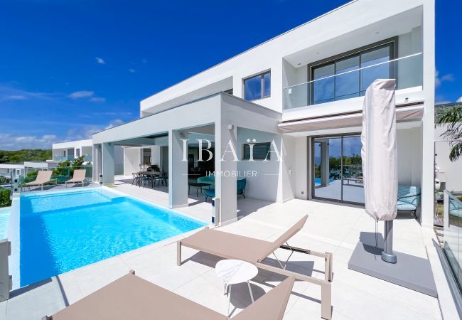 Overflowing pool, deckchairs and parasol on a shaded terrace facing the sea