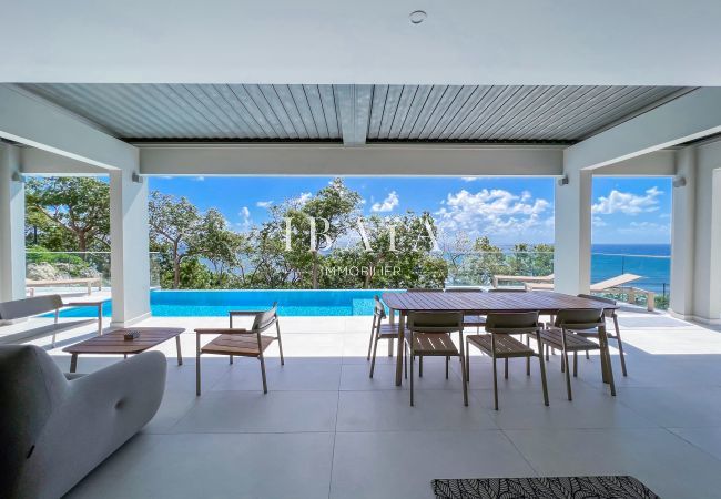 Large living room open to the terrace and outdoor dining area in front of the pool with view on merc