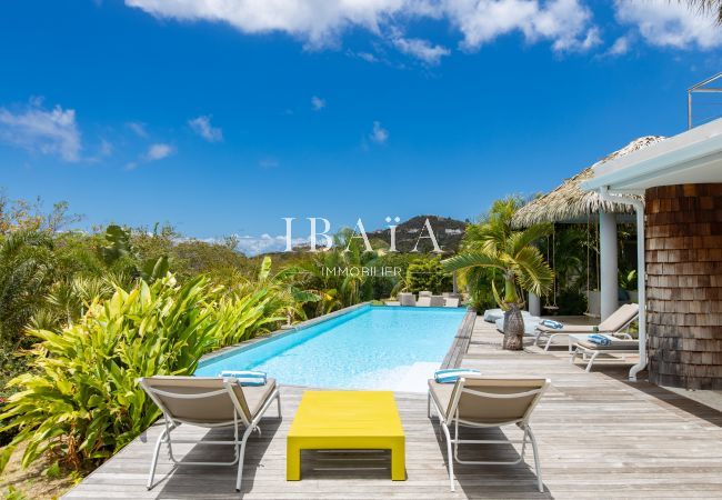 View of the large rectangular swimming pool with deckchairs and wooden terrace in our luxury villa in the West Indies