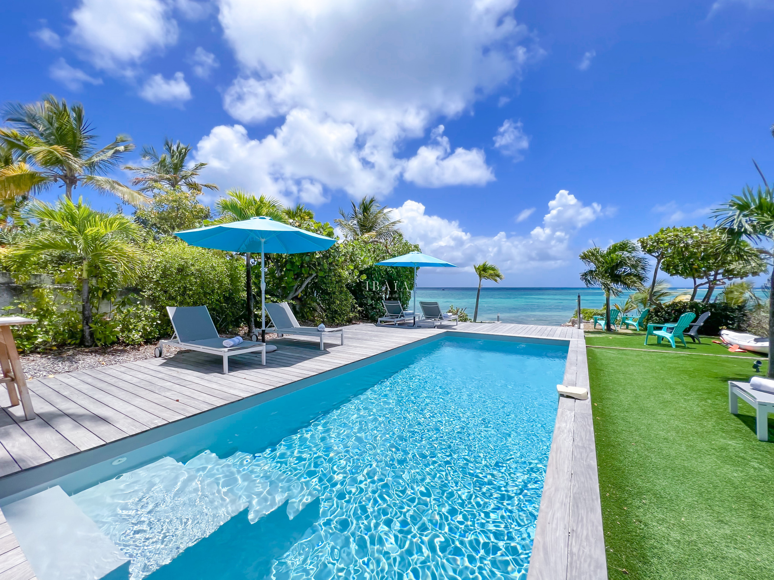 Rectangular swimming pool with sea view, 4 deckchairs, 2 parasols and wooden terrace - Luxury villa in the French West Indies