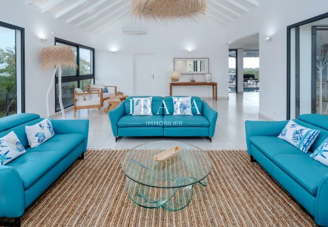 Bright living room with blue sofas, straw hanging lamp, and glass coffee table.