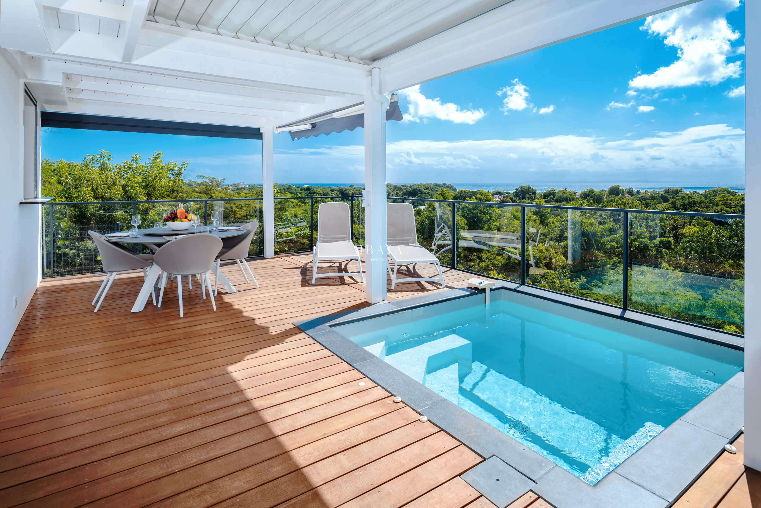 Terrace with dining table, chairs, and a small pool overlooking a natural landscape