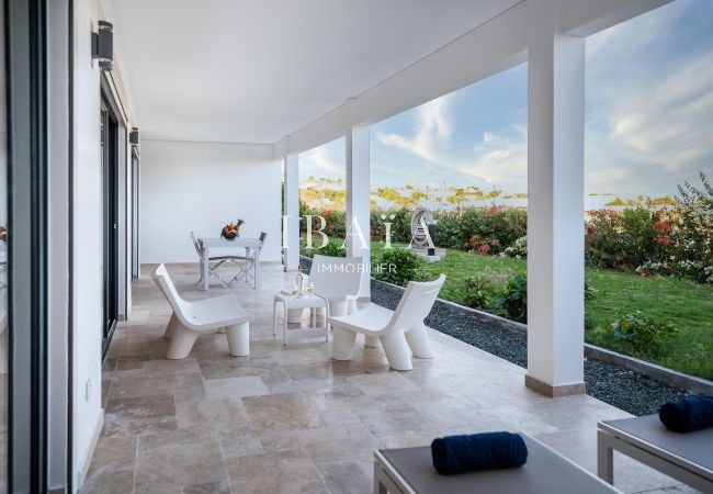 Covered terrace of a modern house overlooking a flowered garden.