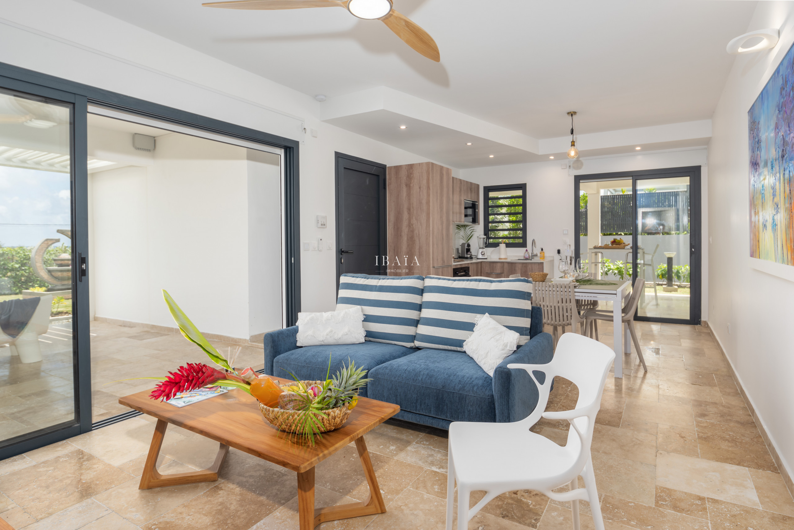 Modern living room with striped sofa, wooden coffee table, and view into the kitchen.