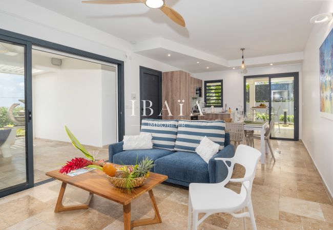 Modern living room with striped sofa, wooden coffee table, and view into the kitchen.