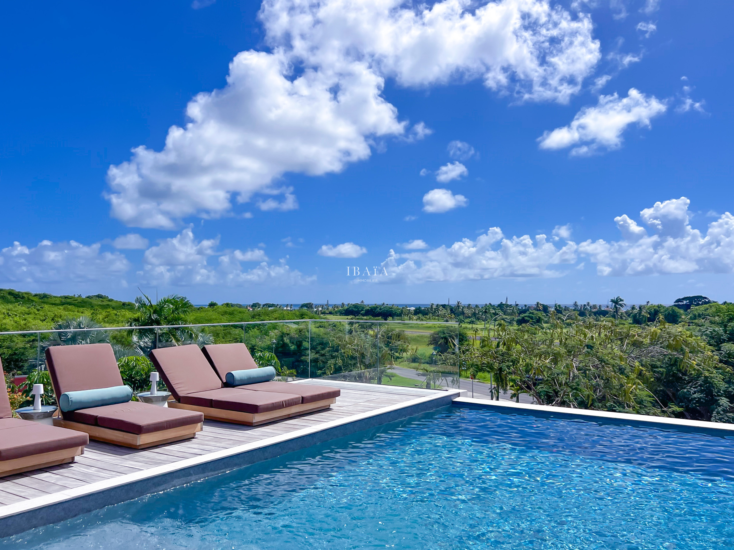 Sun loungers and infinity pool overlooking tropical greenery