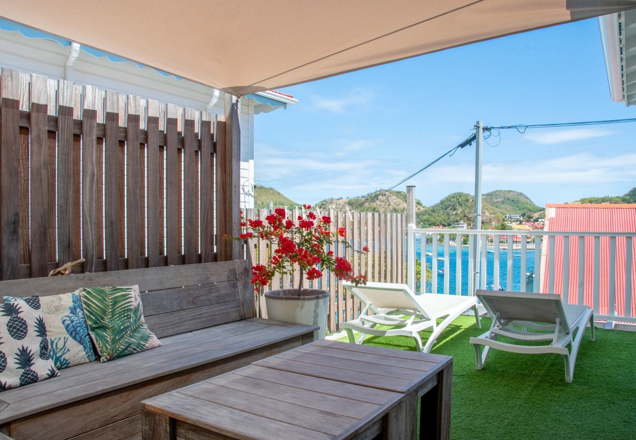 View of the shaded terrace with wooden bench and table, as well as two deckchairs, in a luxury villa in the West Indies