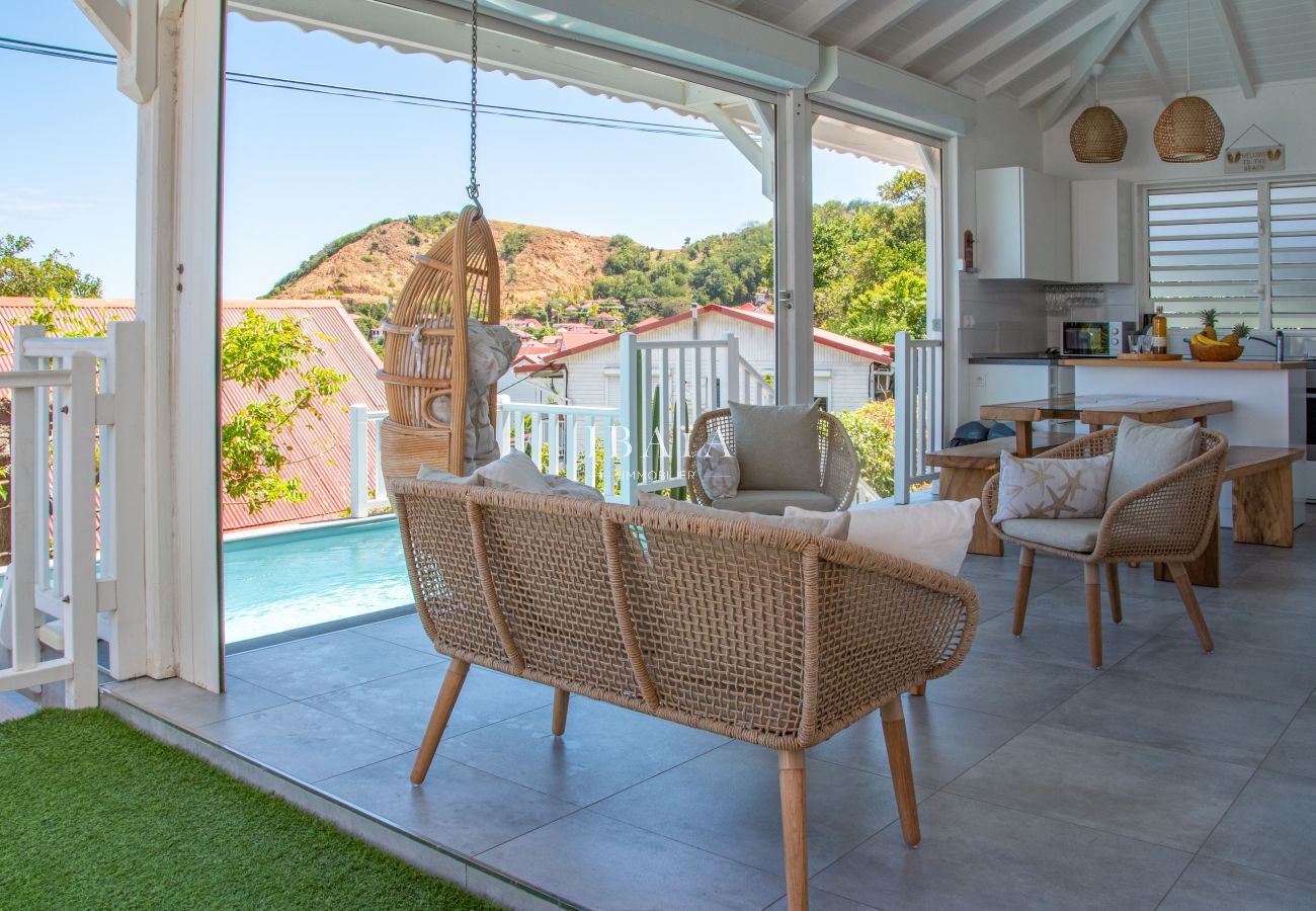 View of the outdoor living room, pool and kitchen area in a high-end villa in the West Indies, for a luxury outdoor living experience.
