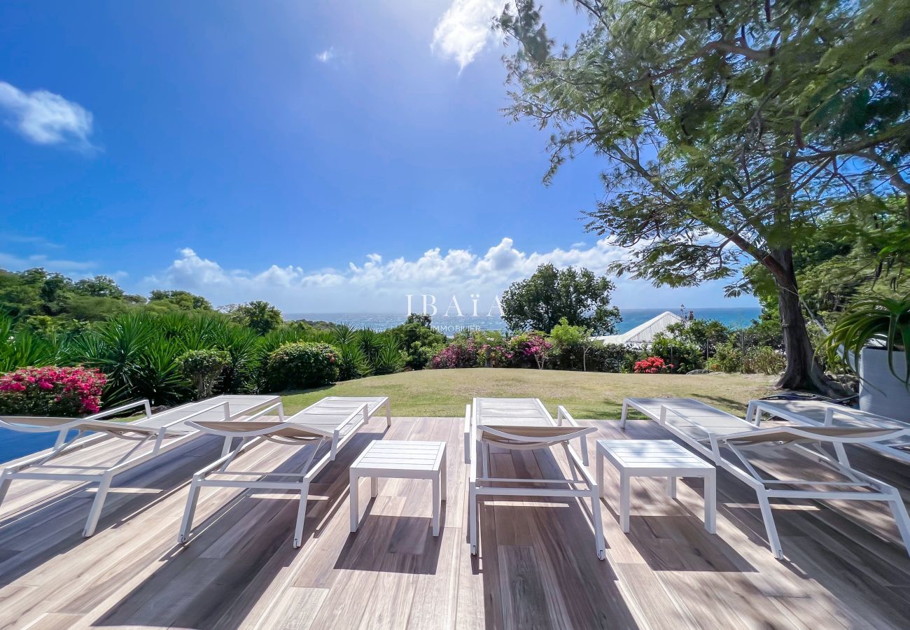 Ocean view from wooden terrace with sunbeds and tropical garden
