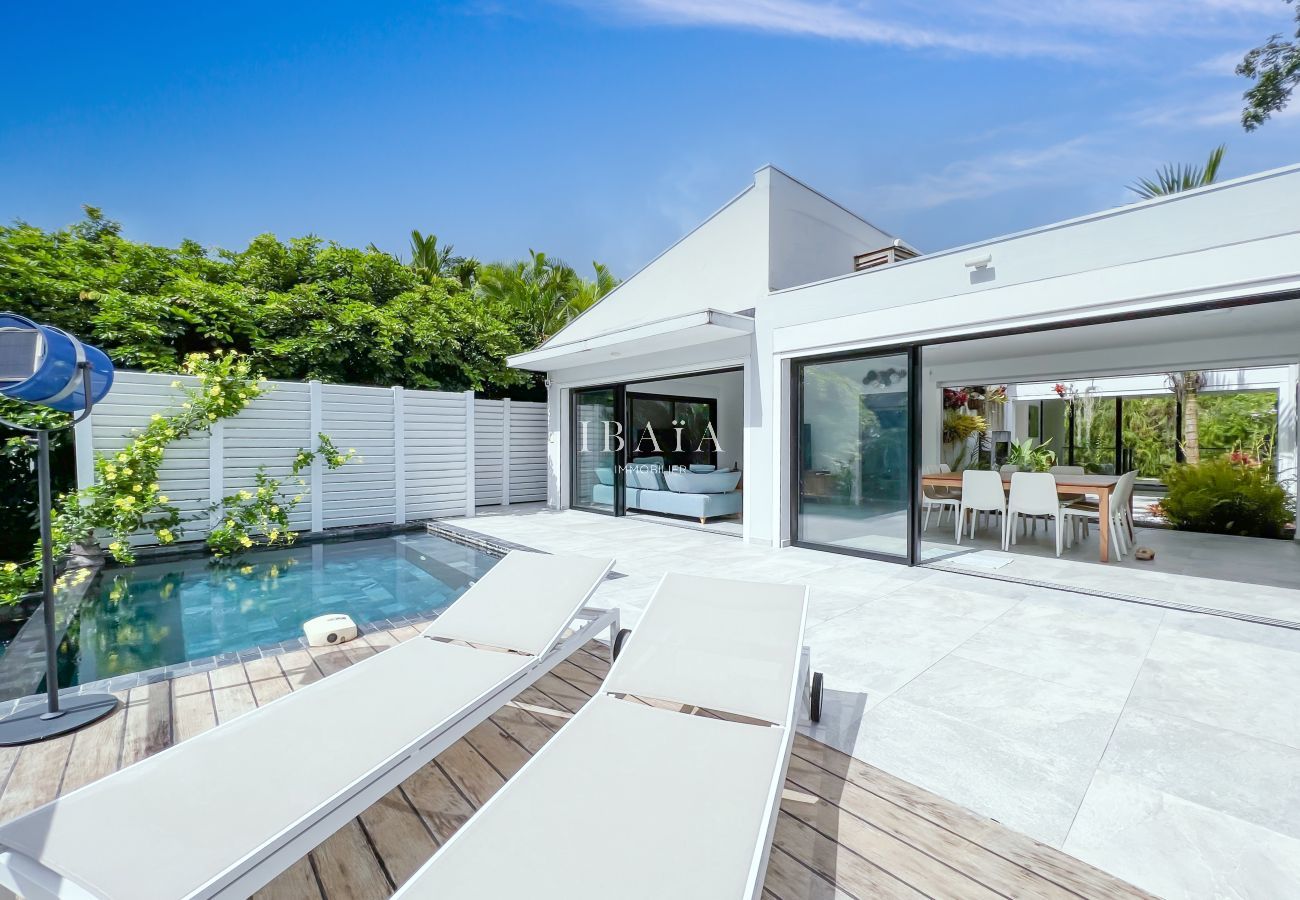 View on the outside terrace, the swimming pool and its 2 deckchairs and view on the dining room and the living room open on the outside thanks to larg