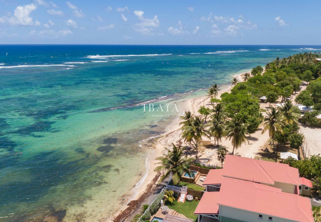 Aerial view of our beachfront villa with a turquoise sea, a magnificent white sandy beach and a coral reef in the background.