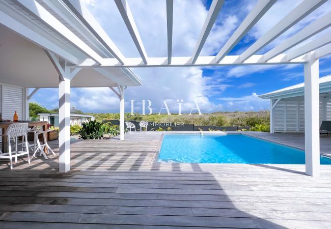 Vista de la terraza con piscina y pérgolas de una villa de alta gama en las Antillas, para una experiencia de relajación absoluta.