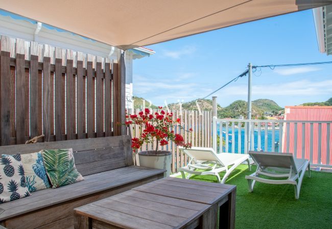 Vista de la terraza sombreada con banco y mesa de madera, y dos tumbonas, en una villa de alta gama en las Antillas.