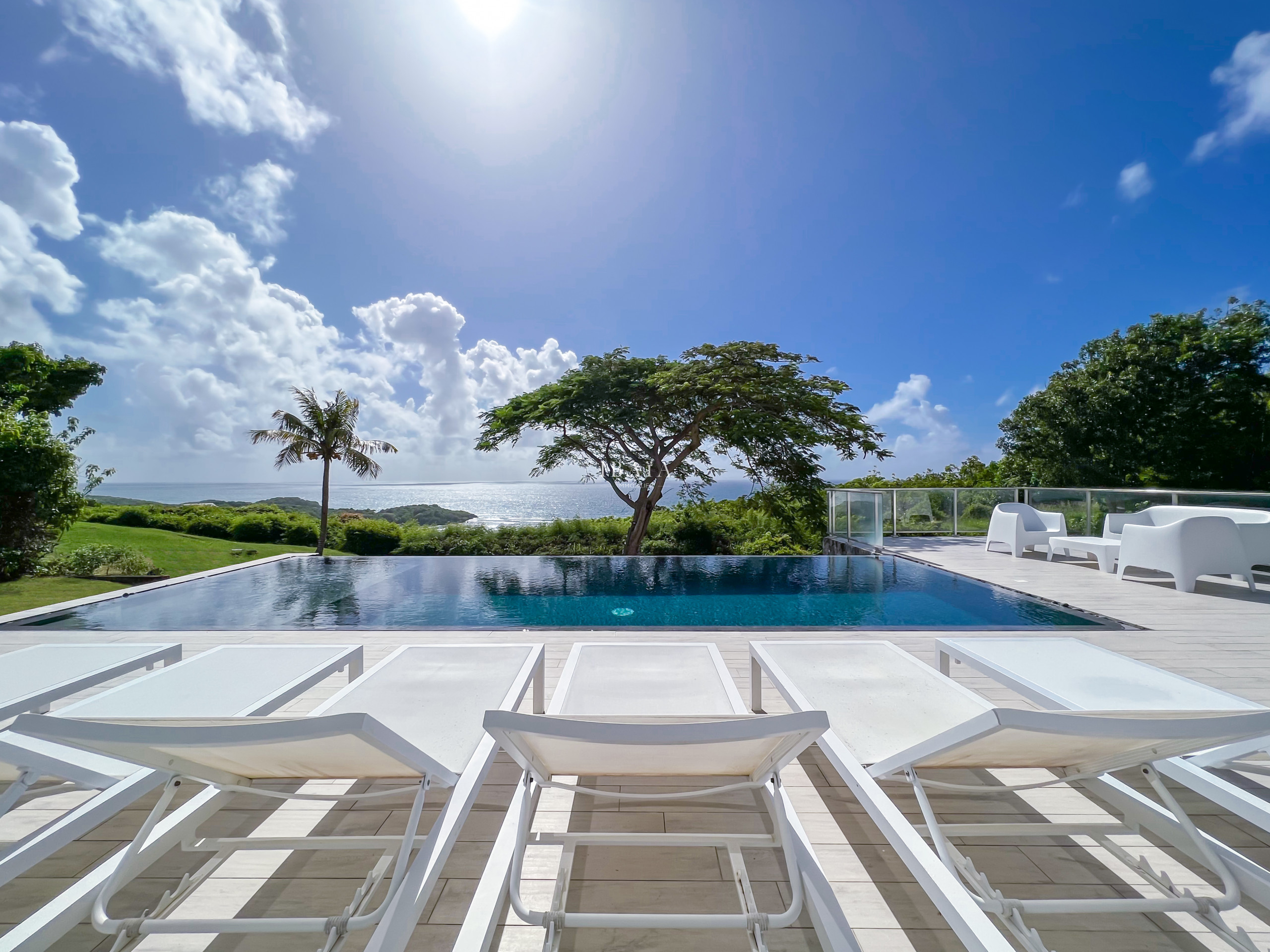 Vista de la piscina infinita, el jardín y el mar desde la terraza de la casa