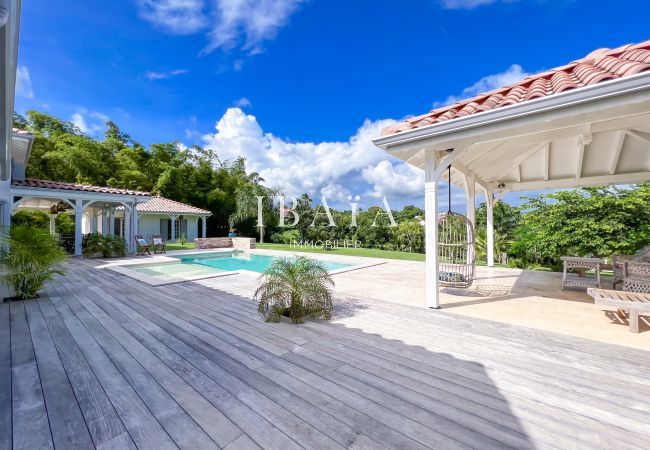 Gran terraza de madera y patio con muebles de jardín con vistas a la piscina