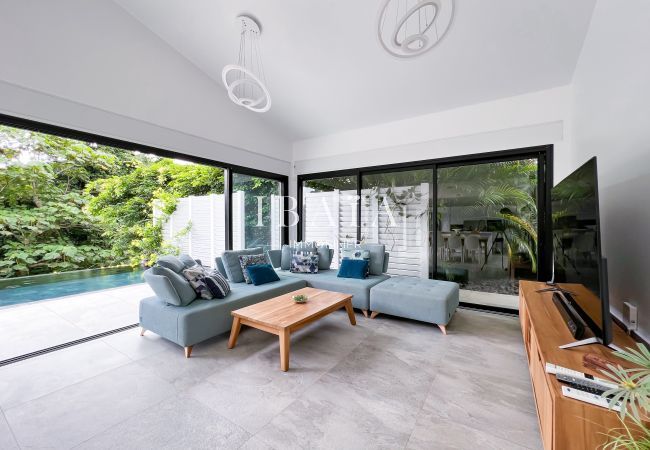 Salón con TV y grandes ventanales a la piscina infinita y a la terraza exterior