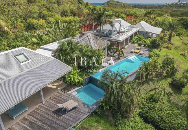 Vista aérea de la piscina y la villa en su jardín tropical desde nuestra villa de lujo en las Antillas