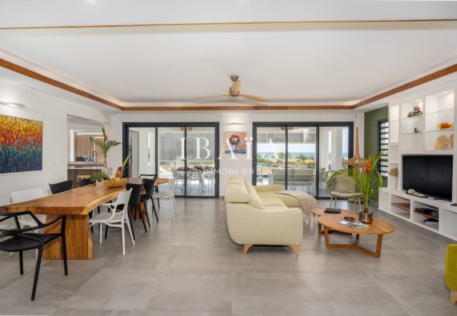 Salón espacioso con mesa de madera, obras de arte y vistas al exterior.