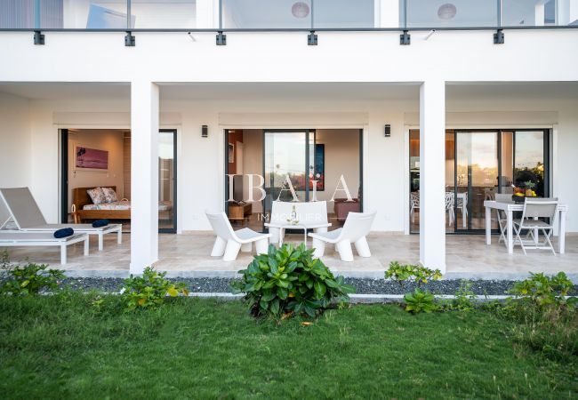 Fachada exterior de una casa moderna con puertas de vidrio y área de relajación.