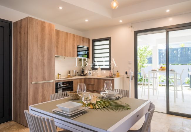 Cocina moderna con detalles en madera, una mesa puesta y vista al jardín.