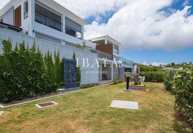 Casa moderna con jardín paisajístico, escultura de cara en piedra y otros elementos decorativos.