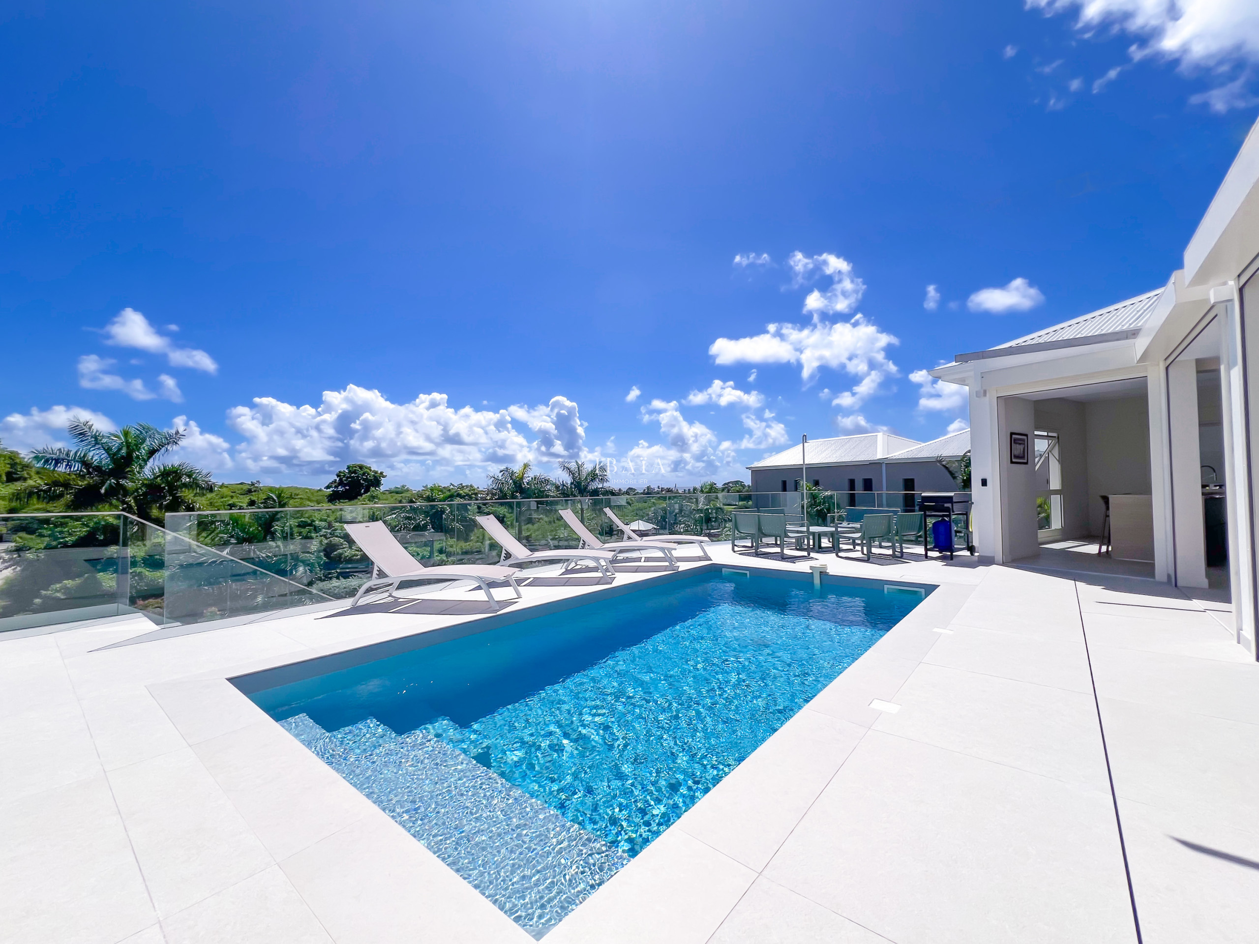 Piscina turquesa y tumbonas bajo el cielo azul