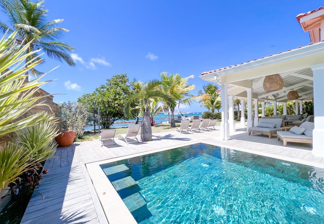 Piscina infinita con vistas al mar, tumbonas y salón exterior en una villa de lujo en las Antillas