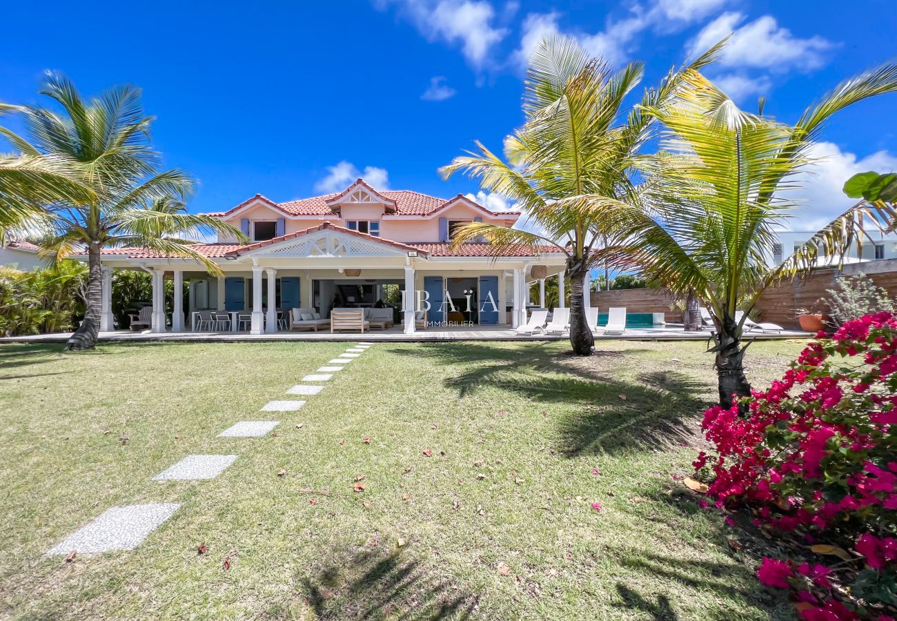 Encantadora vista de la fachada con jardín tropical, terraza y comedor frente al mar en una villa de alta gama en las Antillas