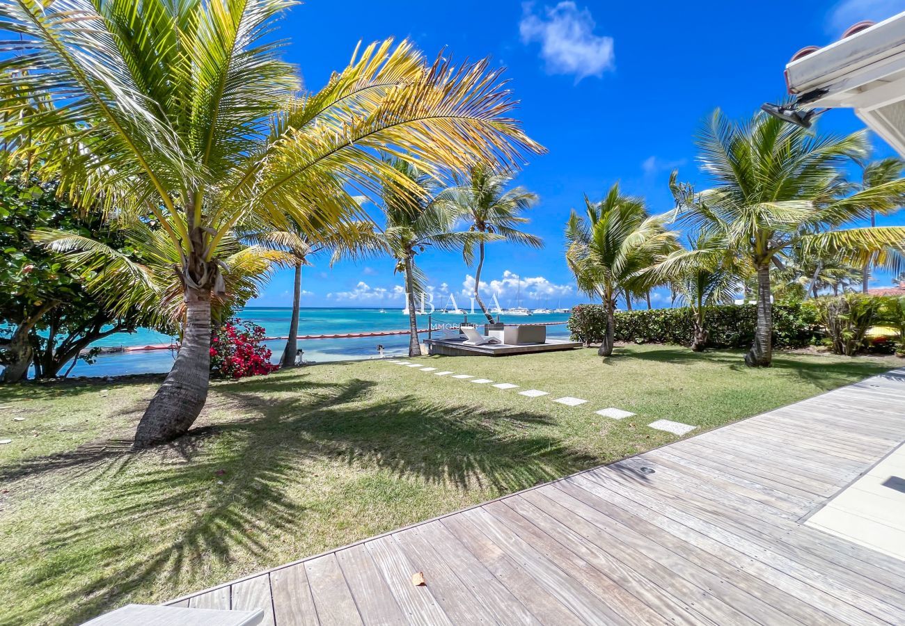 Impresionante vista del jardín, el mar y la laguna de Saint-François desde la terraza de la villa, con cocoteros y buganvillas, en las Antillas.