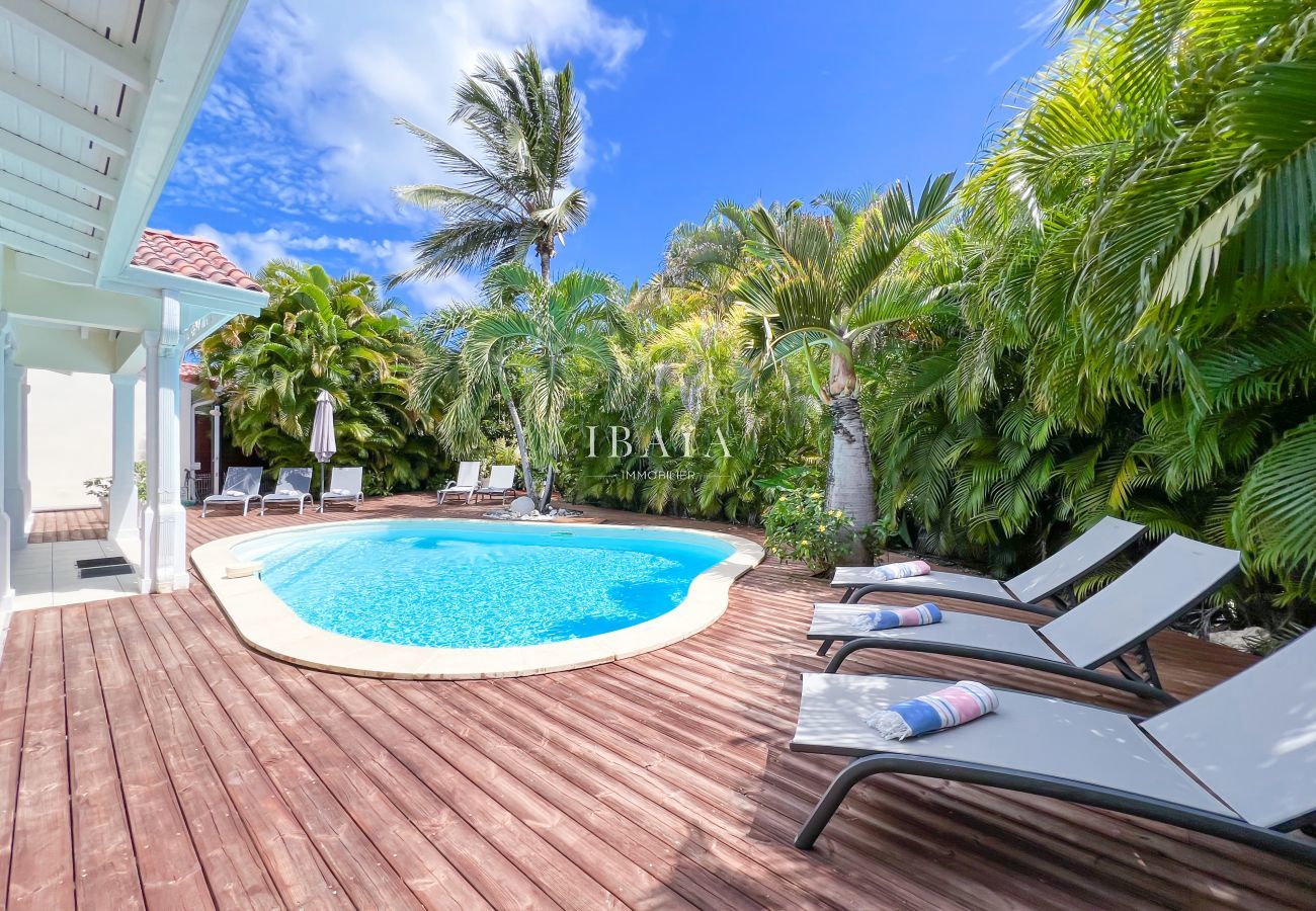Amplia terraza sombreada situada en un jardín tropical con piscina privada
