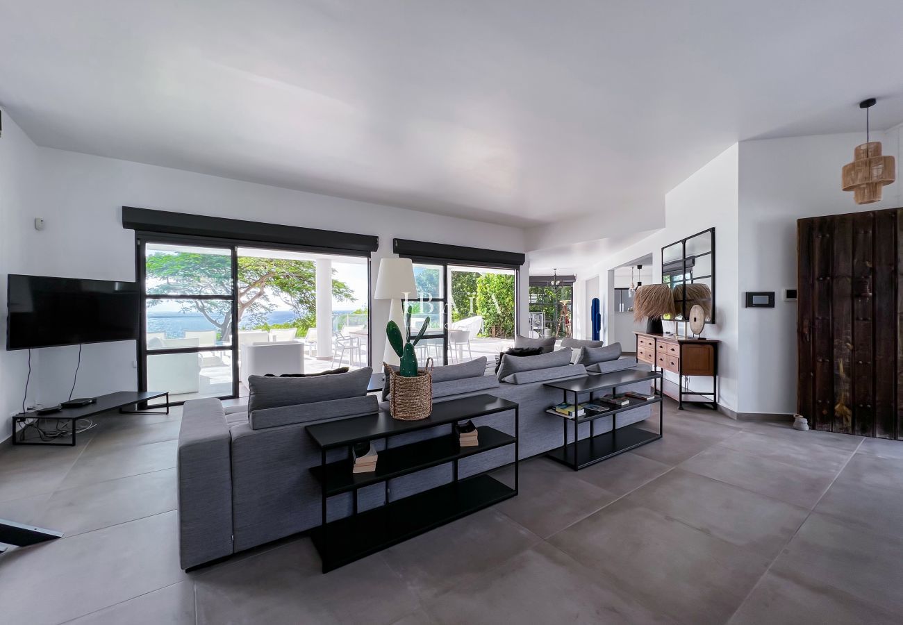 Amplio salón interior con TV y vistas a la piscina y al mar
