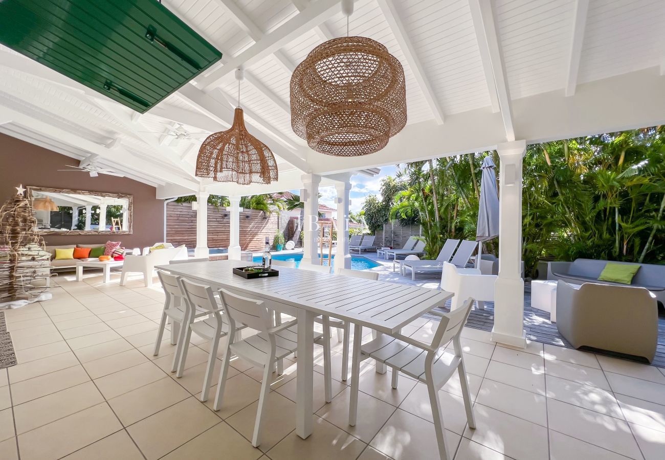 Gran mesa de comedor para 8 personas al borde de la terraza de madera con vistas a la piscina de agua salada