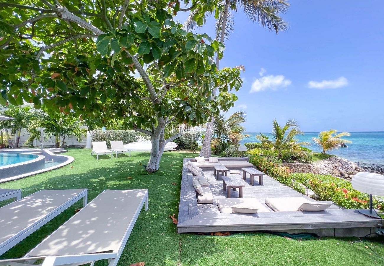 Sala de estar y tumbonas al aire libre con vista al mar en un jardín tropical bien cuidado
