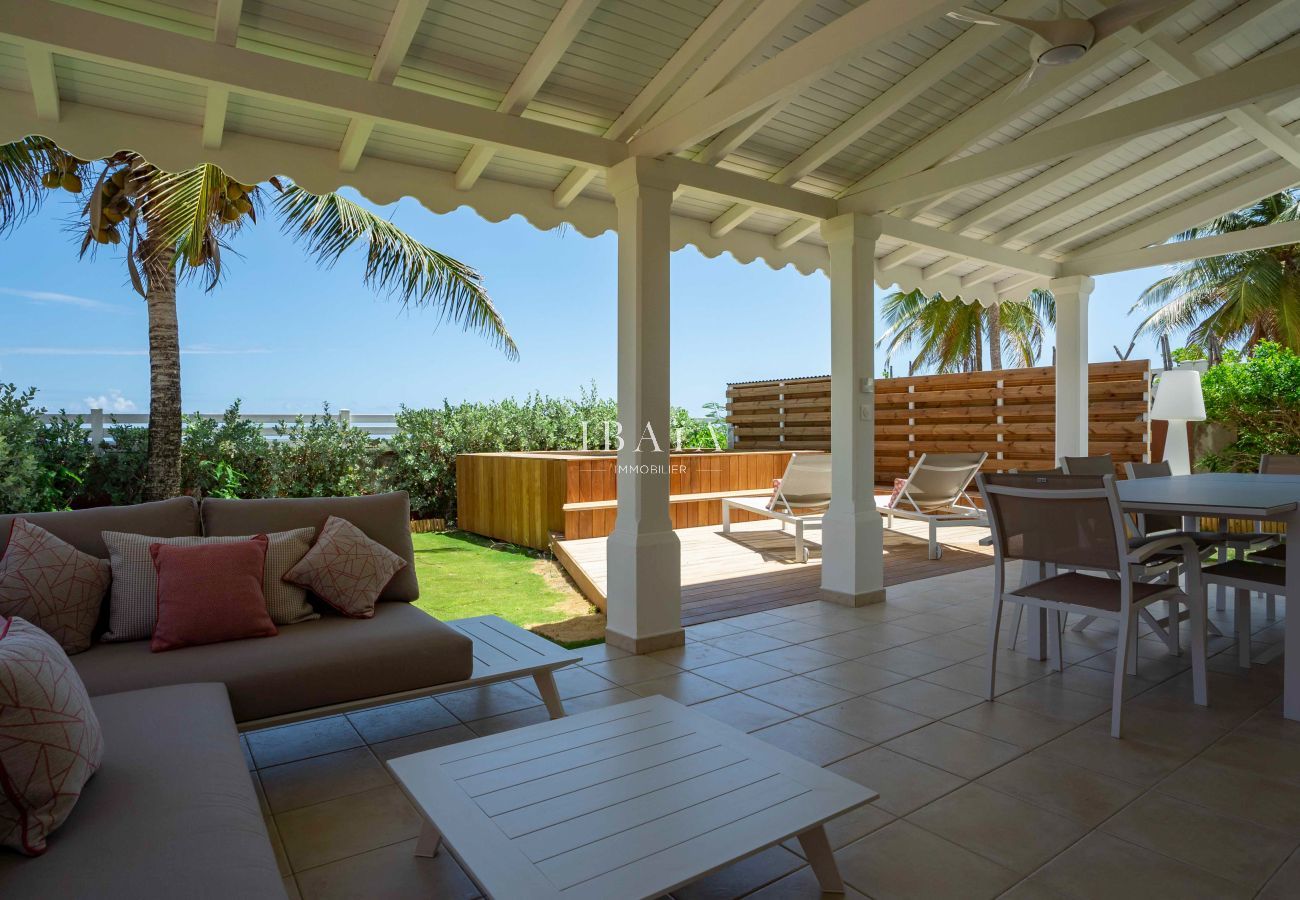 Vista desde la terraza con salón exterior y mesa de comedor con vistas al mar y a la piscina de nuestra villa de lujo en las Antillas.