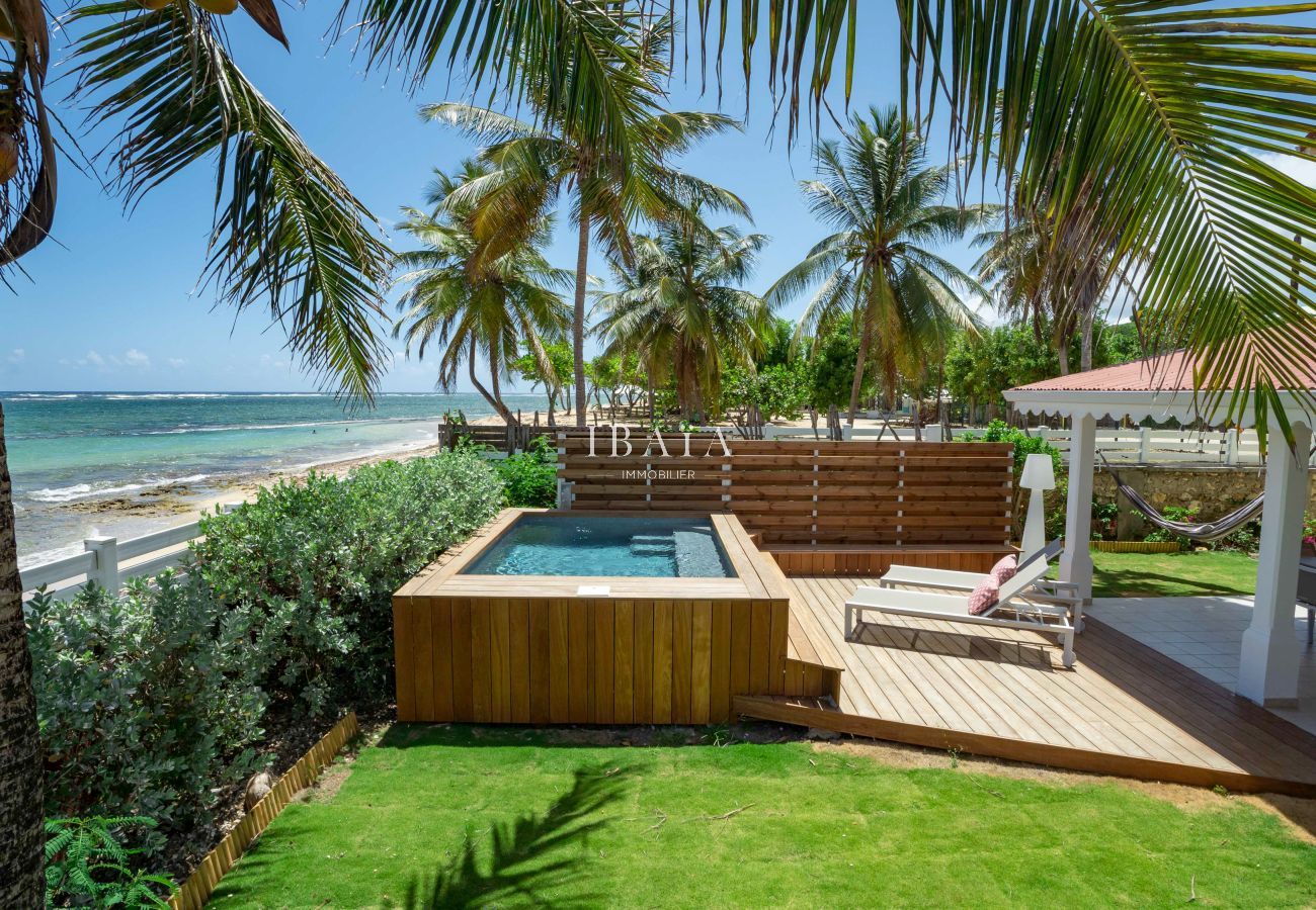 Vista de la piscina, la terraza junto a la piscina y el mar con su playa desde nuestra villa de lujo en las Antillas.