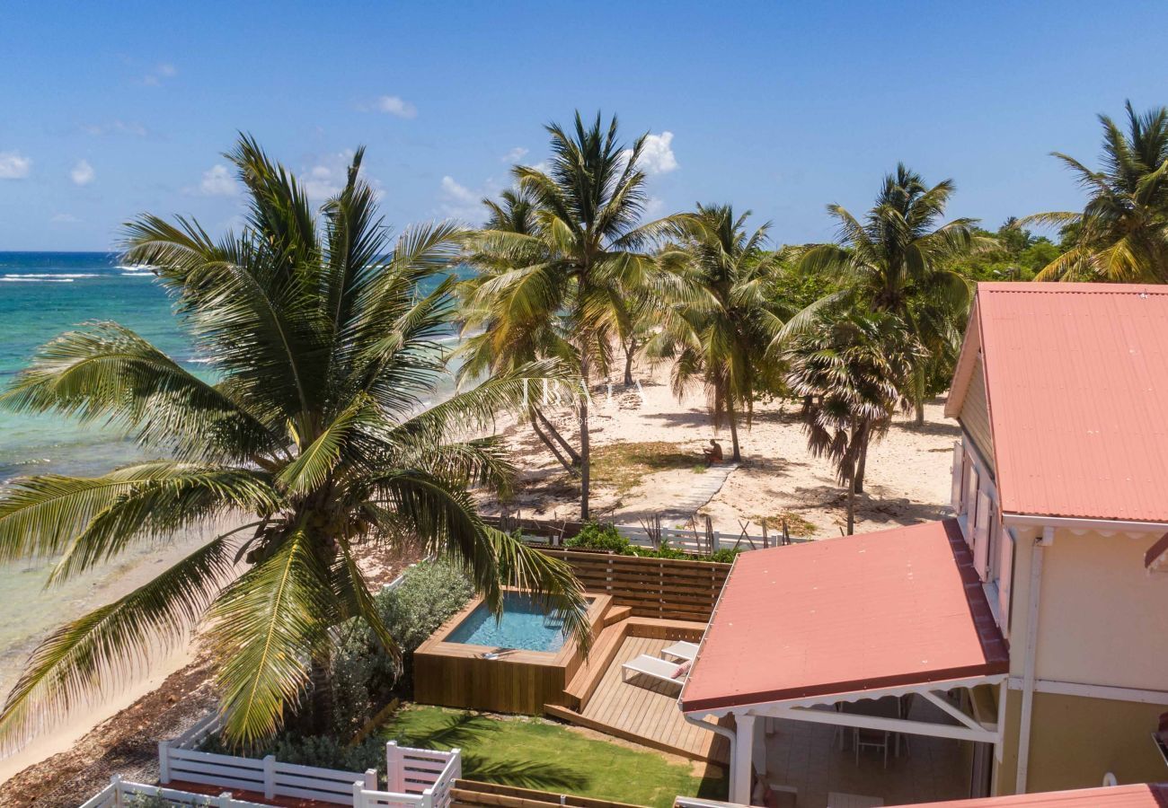 Vista aérea de nuestra villa de alta gama con vistas al mar, la playa y la piscina en el jardín de las Antillas.