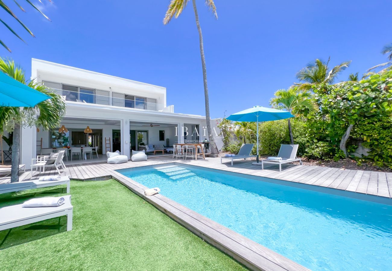 Fachada de villa de lujo con piscina y terraza de madera - Tranquilidad y elegancia en las Antillas