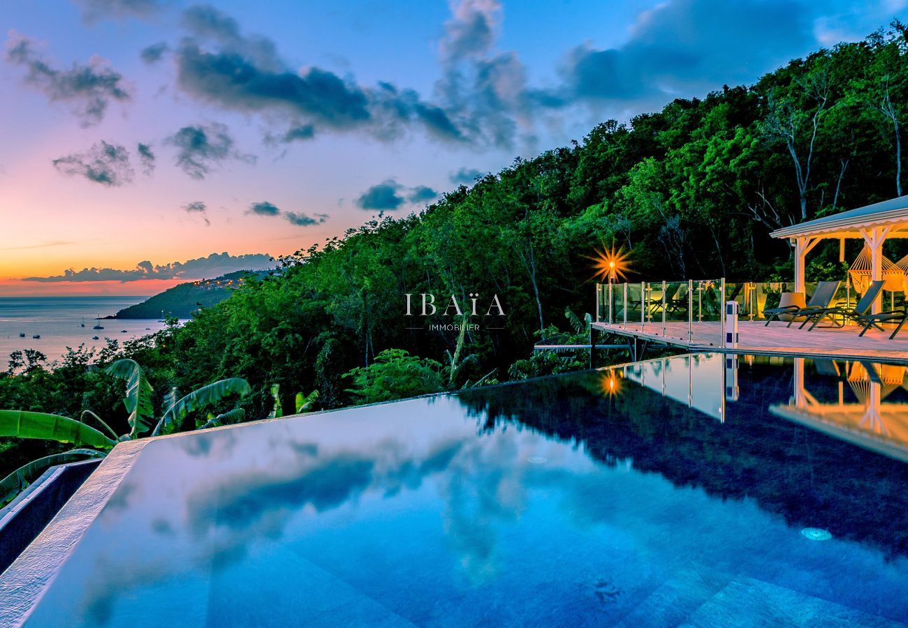 Magnífica puesta de sol sobre la bahía, con la piscina y la terraza de la villa en las Antillas ofreciendo vistas panorámicas al mar