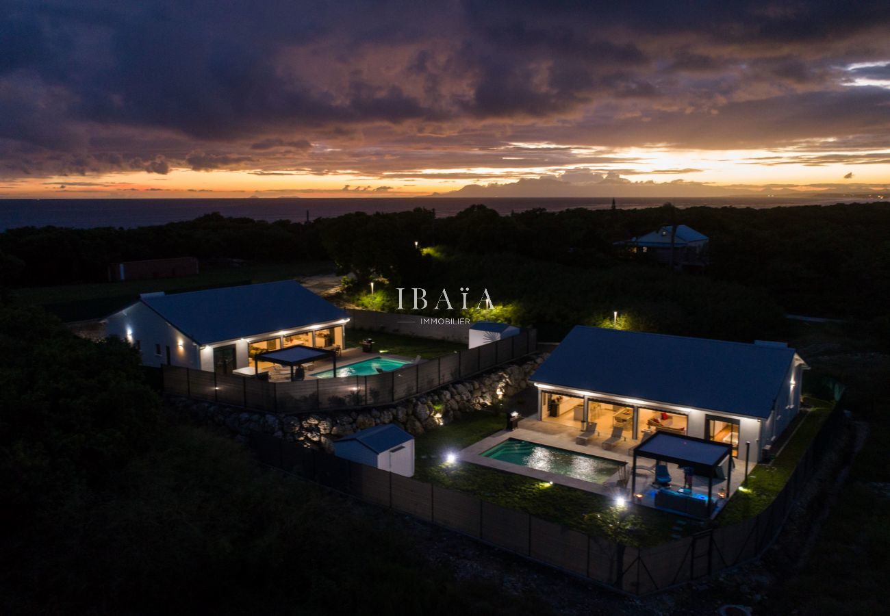 Vista aérea nocturna de la villa iluminada con piscina centelleante, en un alquiler de alta gama en las Antillas