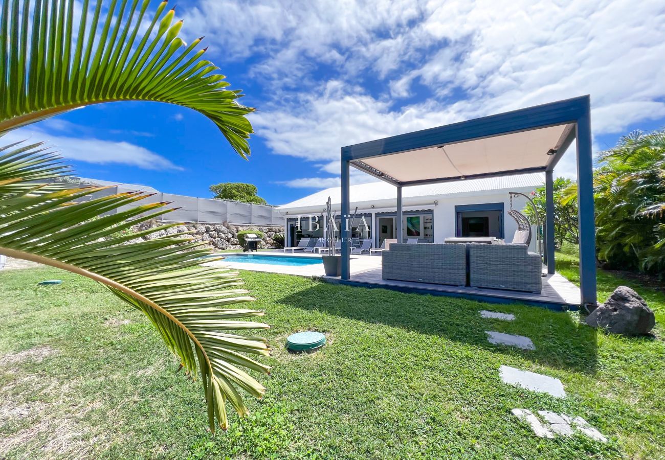 Espectacular vista desde la pérgola con salón exterior, piscina y terraza de la villa de gama alta en las Antillas