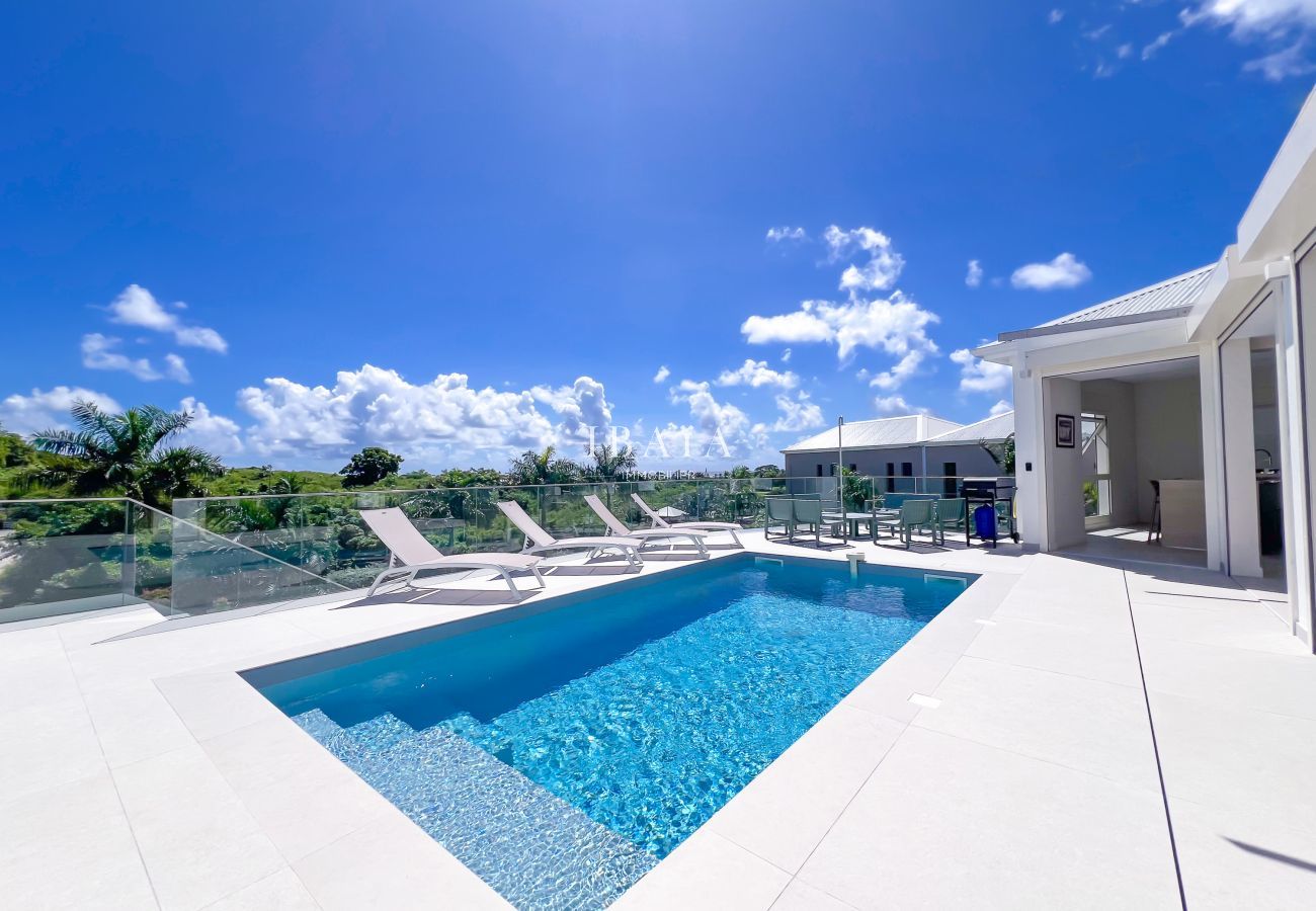 Piscina turquesa y tumbonas bajo el cielo azul