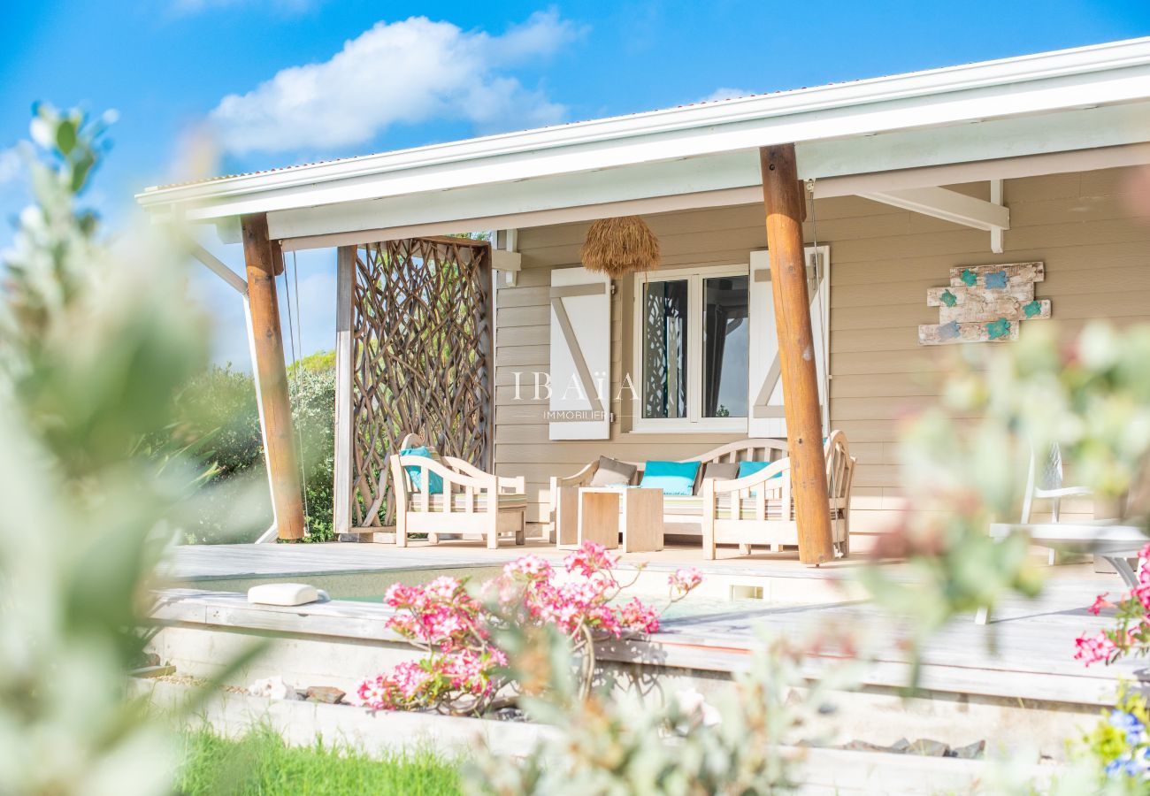 Casa criolla de madera con terraza, muebles naturales y flores tropicales