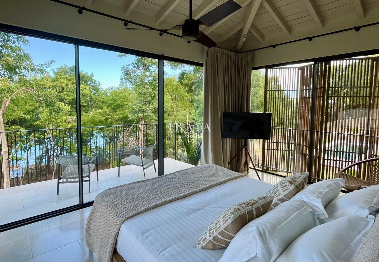 Dormitorio moderno con grandes ventanales, terraza y vista natural