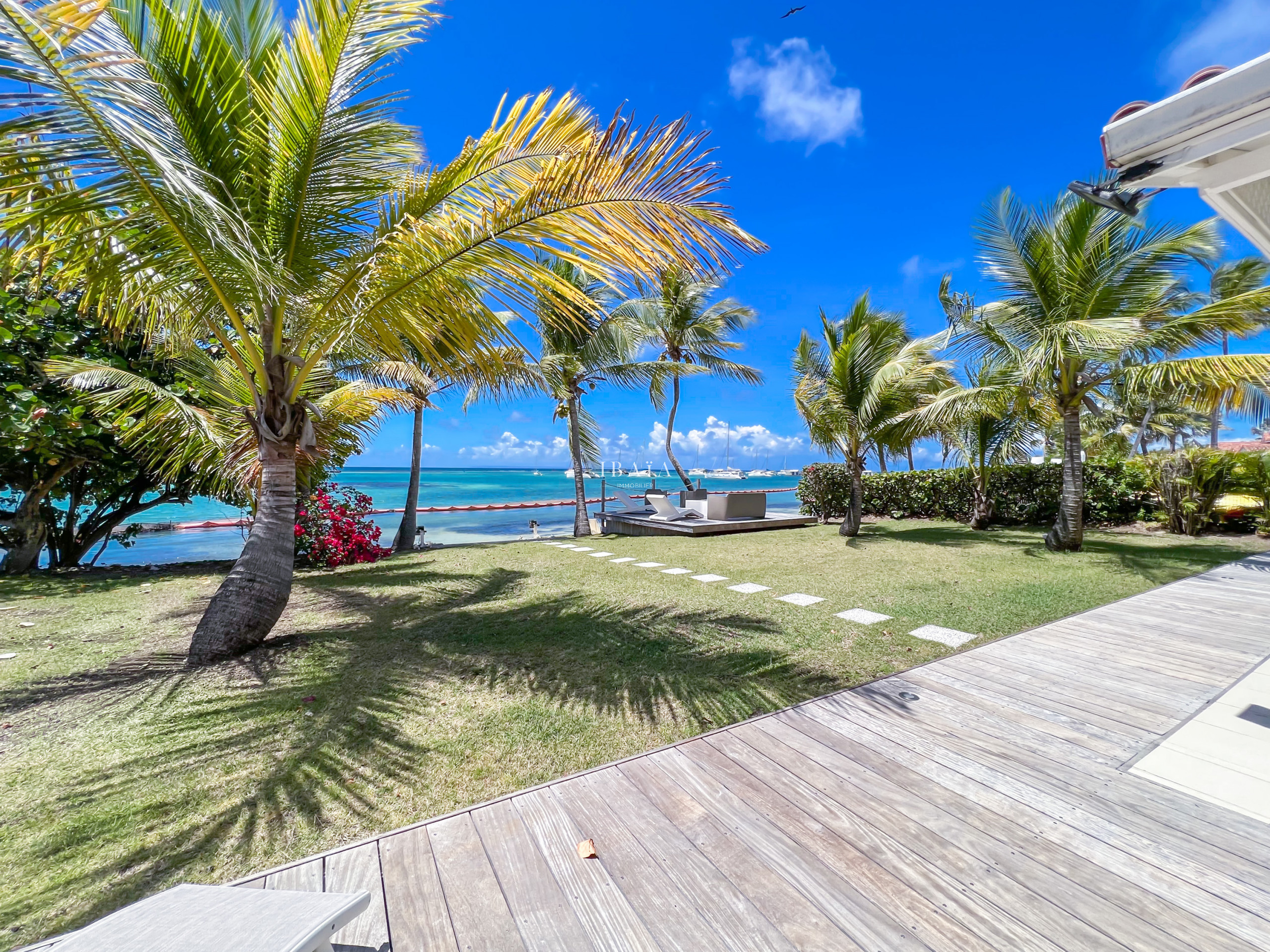 Vue imprenable sur le jardin, la mer du lagon de Saint-François depuis la terrasse de la villa, avec cocotier et bougainvillier, aux Antilles