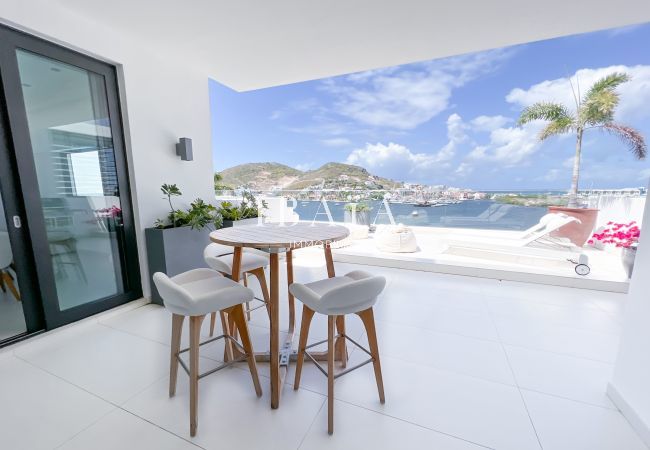 Vue de la terrasse du penthouse avec table et chaise haute d'extérieur, offrant une vue panoramique sans vis-à-vis sur la baie, dans une villa haut de