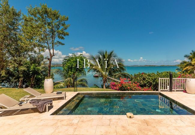 Vue sur la mer et la piscine, avec deux transats, dans une villa haut de gamme aux Antilles, pour des moments de détente au bord de la piscine avec vu